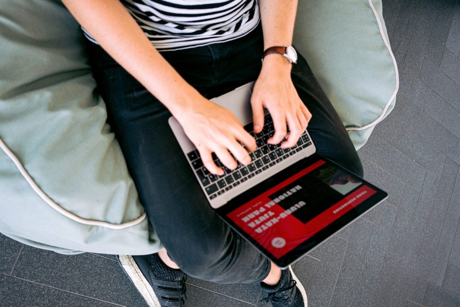 Osoba pisze na laptopie siedząc na poduszce