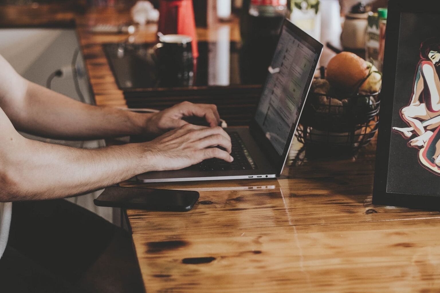 Osoba pracująca na laptopie przy drewnianym stole
